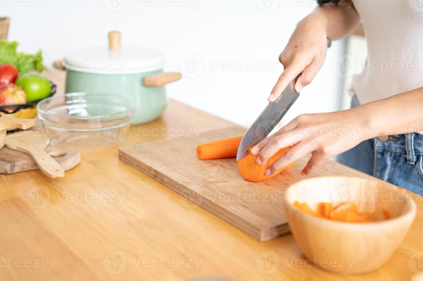 A close-up image of a woman cutting a carrot on a cutting board, cooking in the kitchen. photo