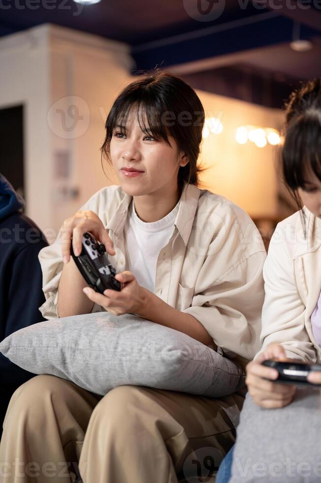 A young, beautiful Asian girl is enjoying playing a game on a couch at home with her friends. photo