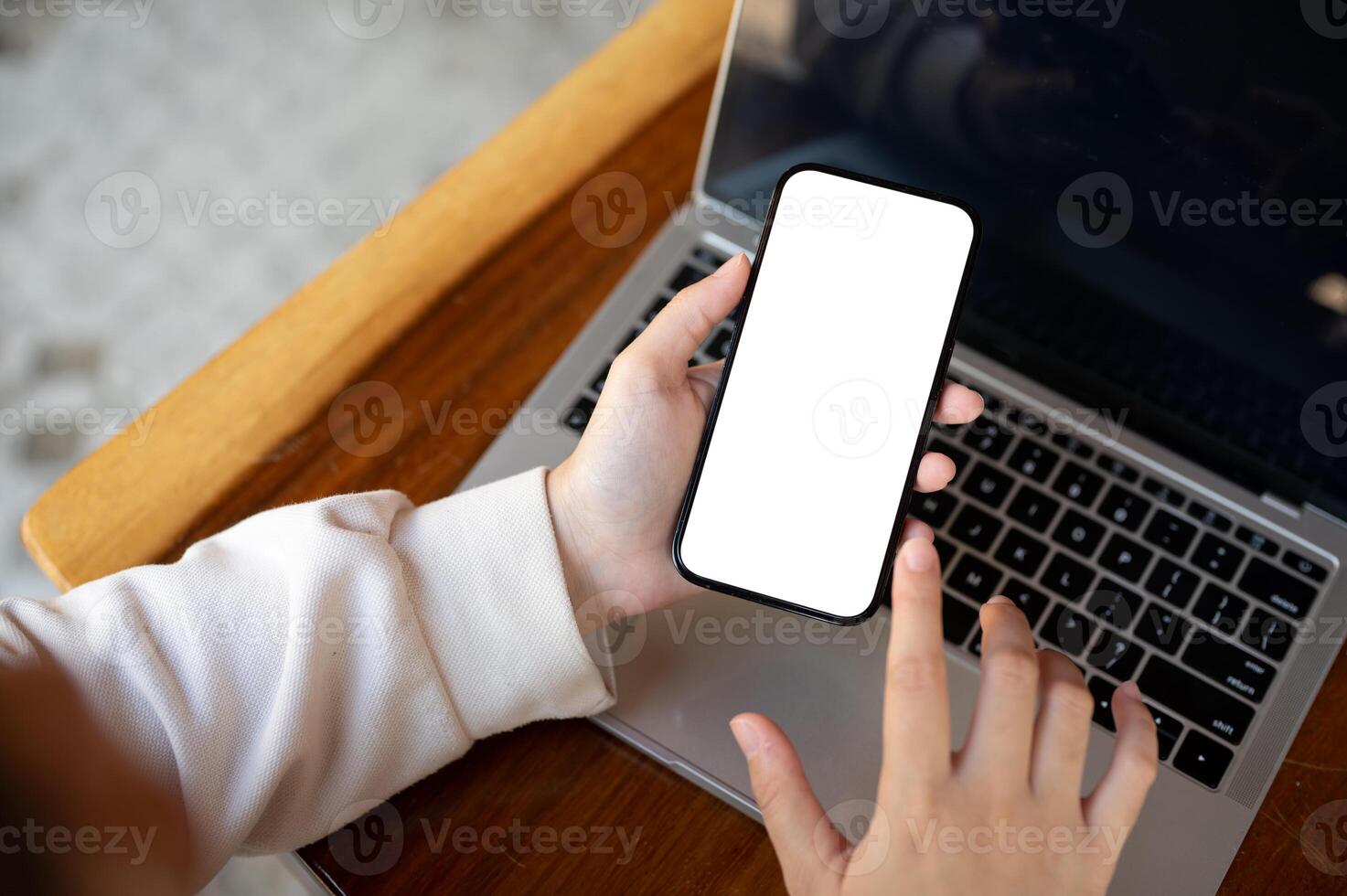 Top view image of a woman using her smartphone at her working desk. A white-screen smartphone mockup photo