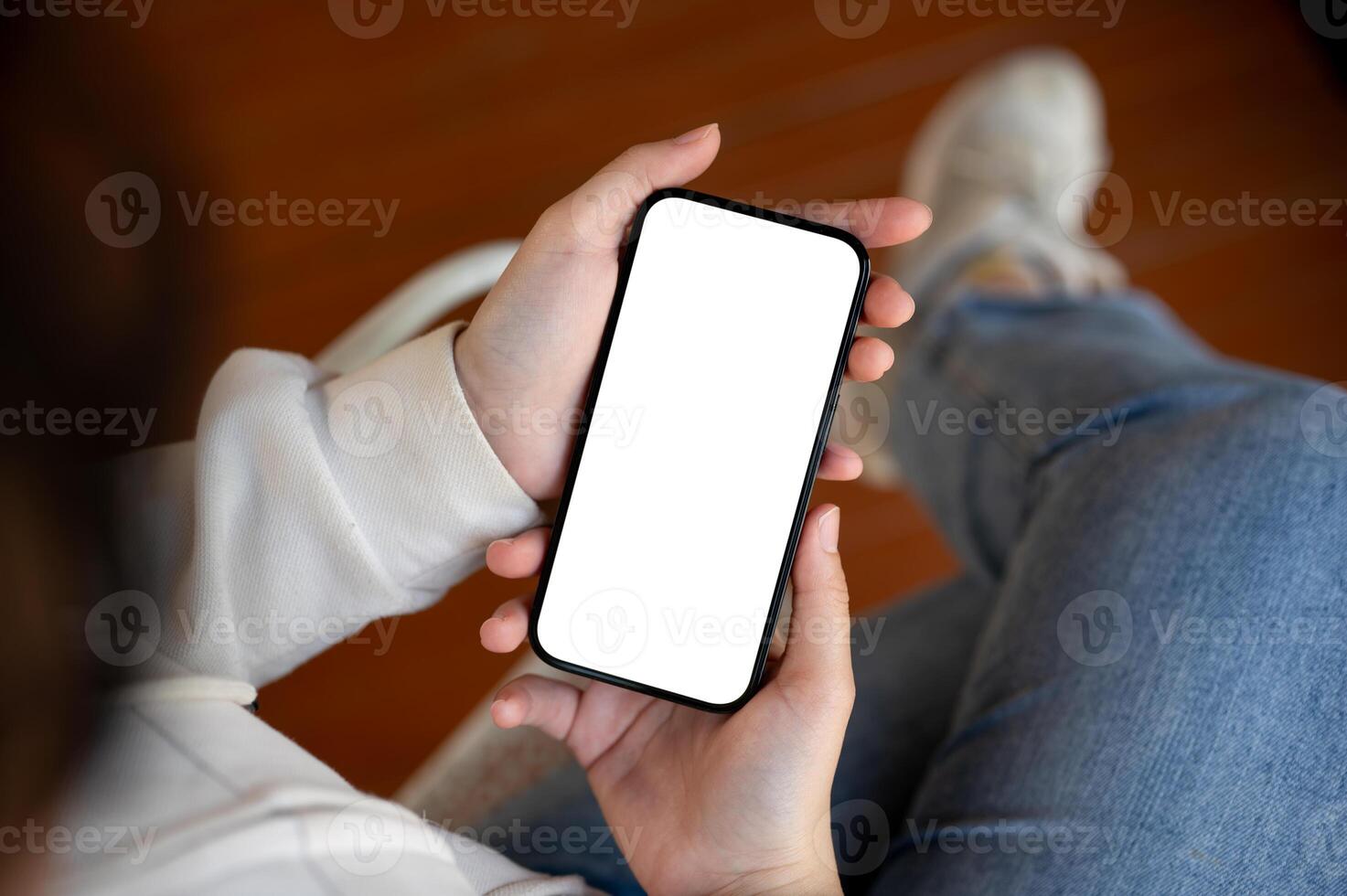 A woman is sitting indoors and using her smartphone. People and technology concepts photo
