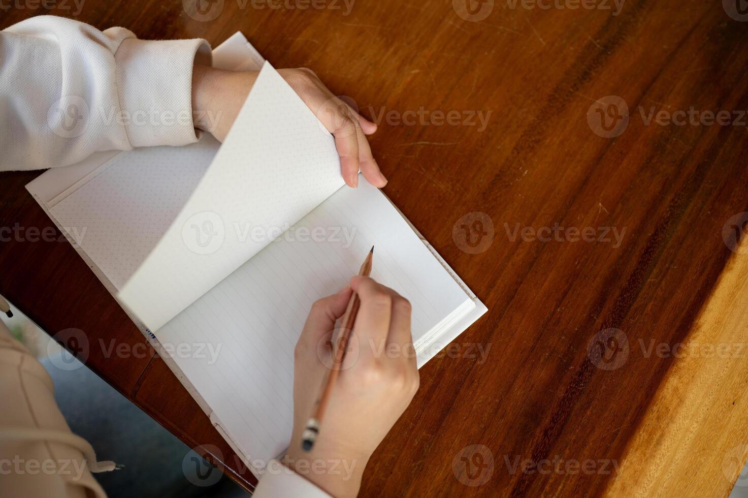 A woman writing something in a book at a table in a cafe. top view image photo