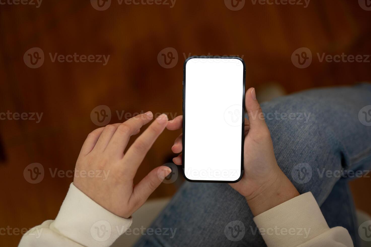 Top view image of a woman in jeans is using her smartphone while sitting indoors. photo