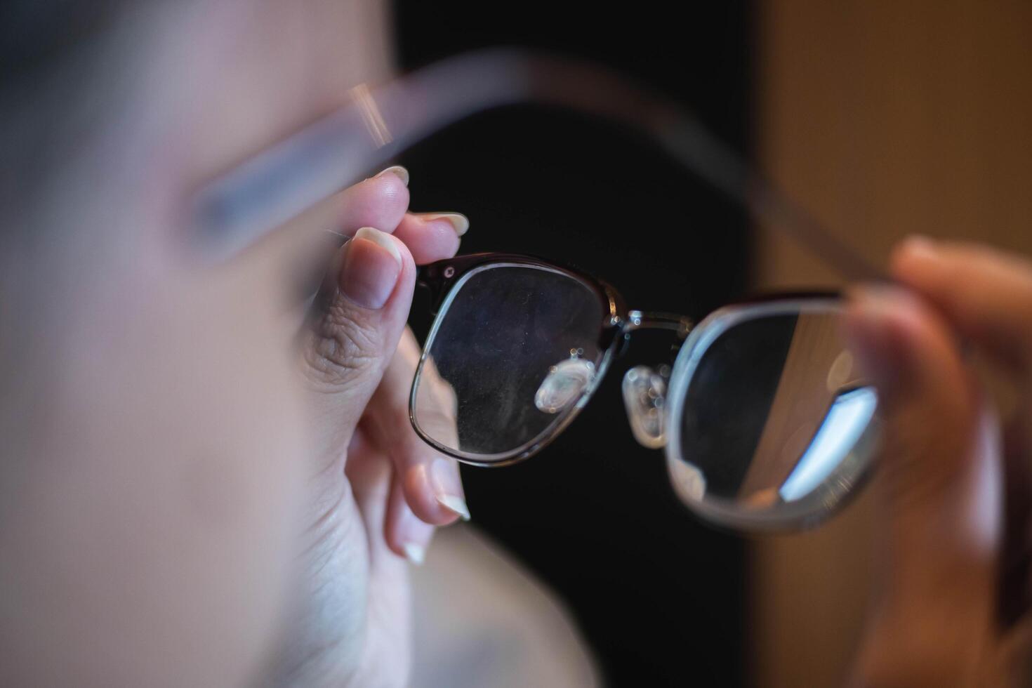 Person holding eyeglasses with smudged lens photo