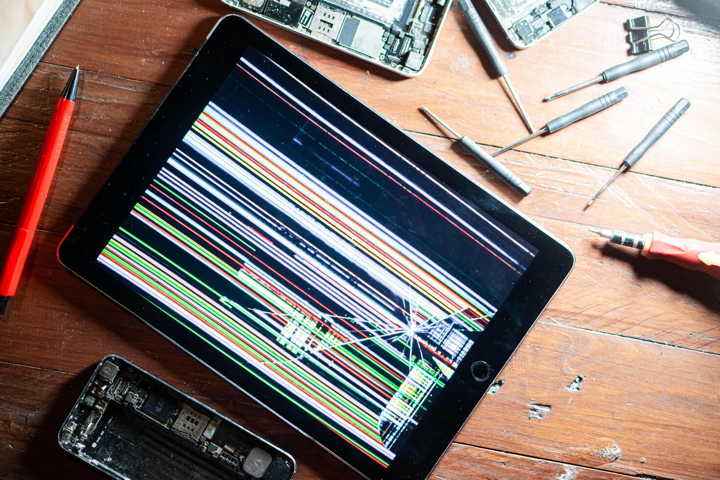 Damaged tablet with distorted screen and repair tools photo