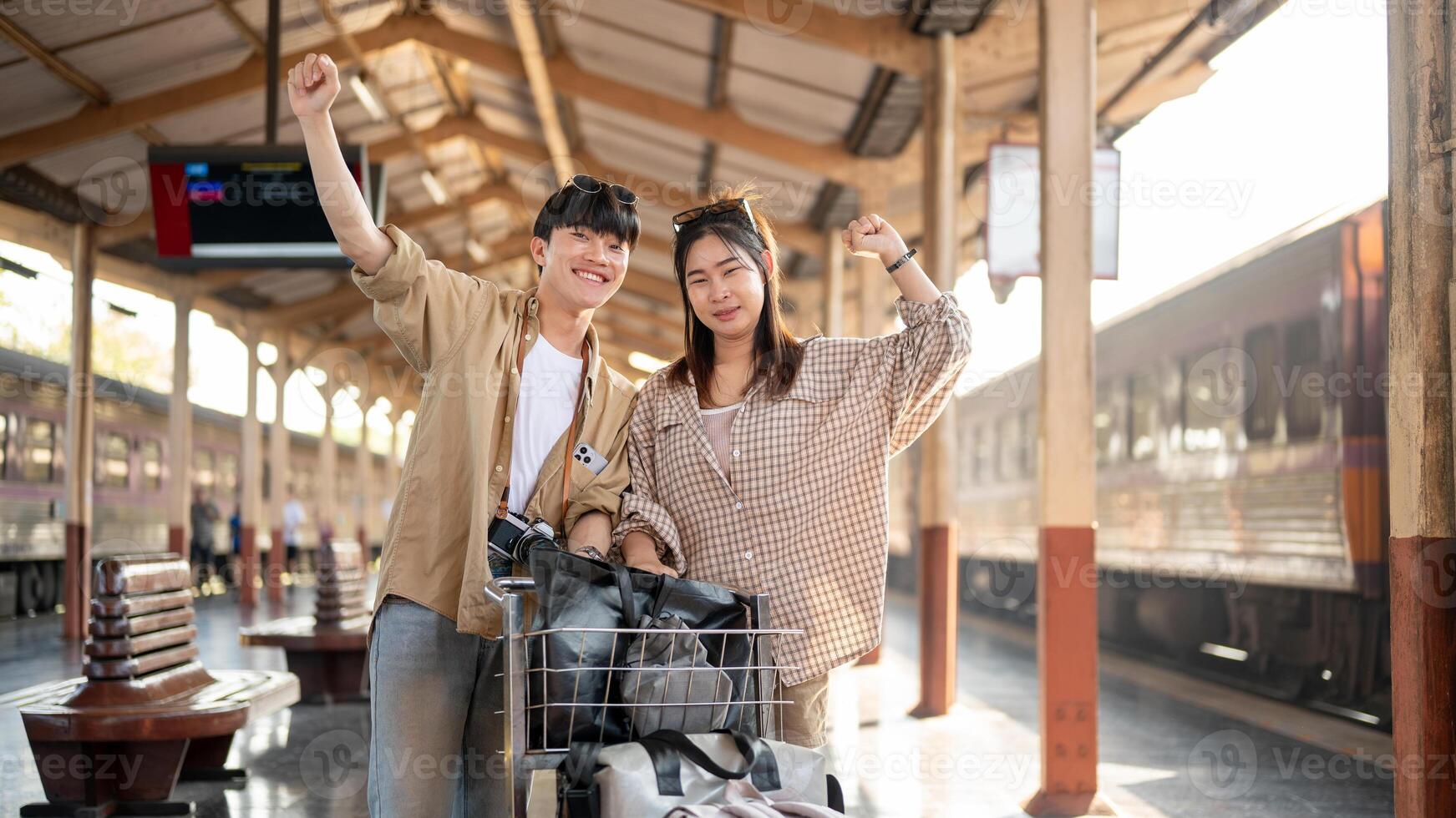 Cute couple are walking down the platform with a cart, commuting by a train at a railway station. photo