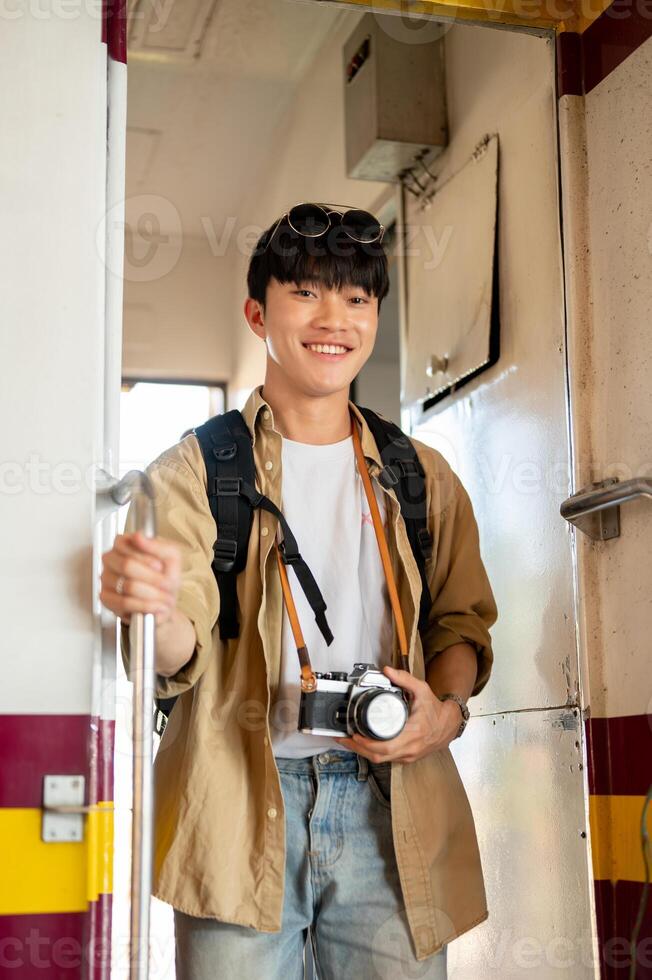 A happy young Asian male traveler backpacker is getting off the train, arrived at his destination. photo