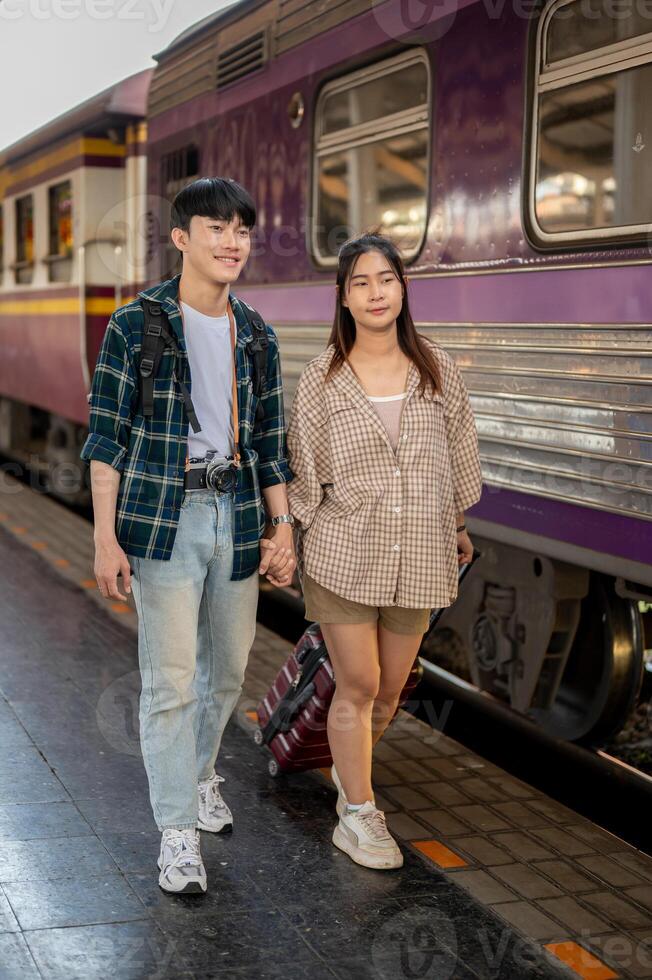 Asian couple travelers are commuting by train together, walking on a platform at a railway station. photo