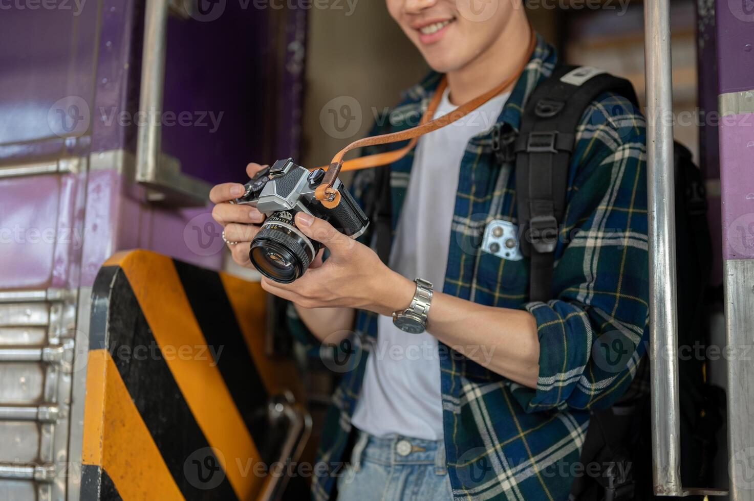 An Asian man traveler backpacker is taking pictures with his camera while getting off the train. photo
