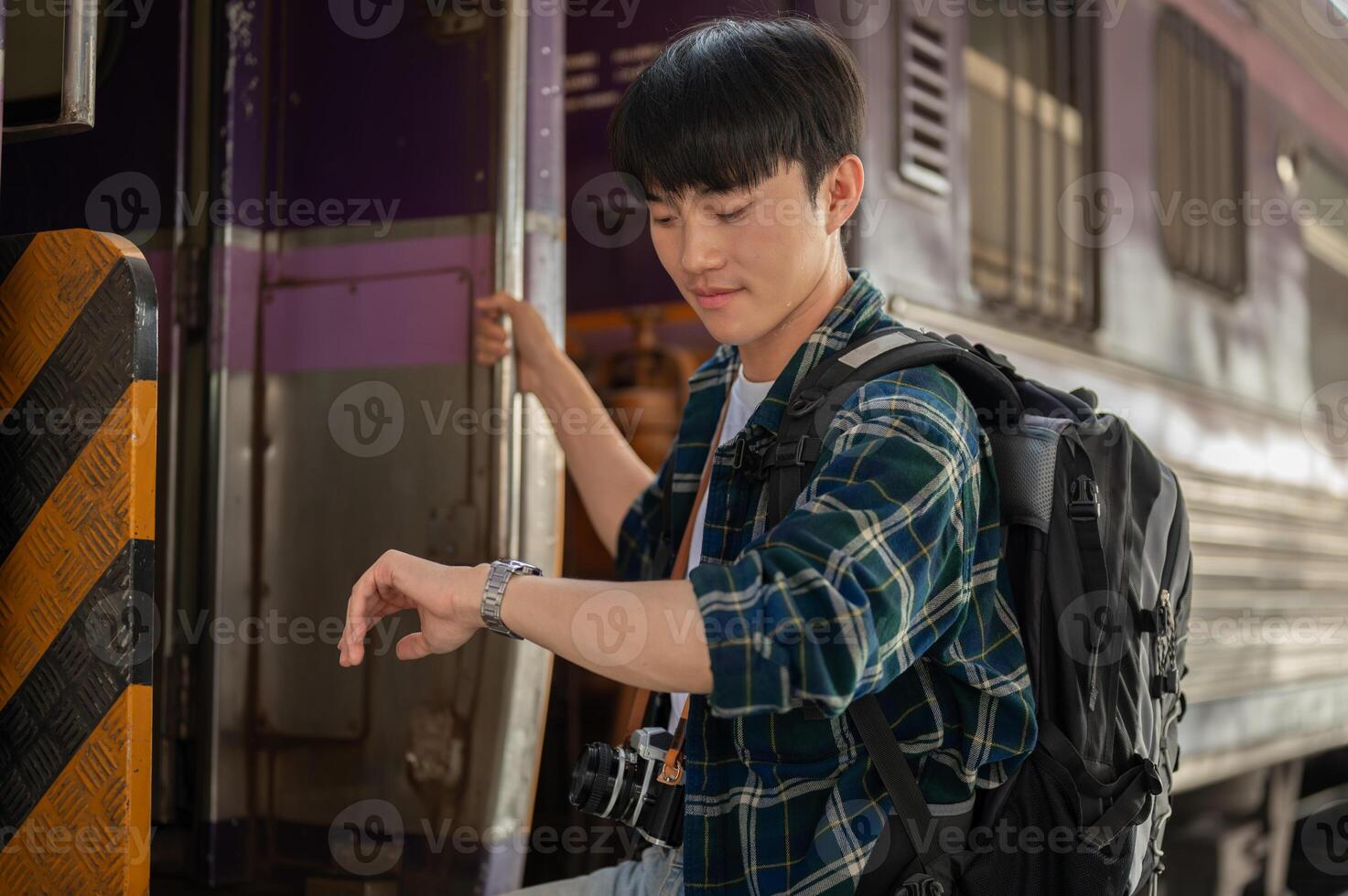 A handsome Asian man traveler is checking time on his wristwatch while getting off the train. photo
