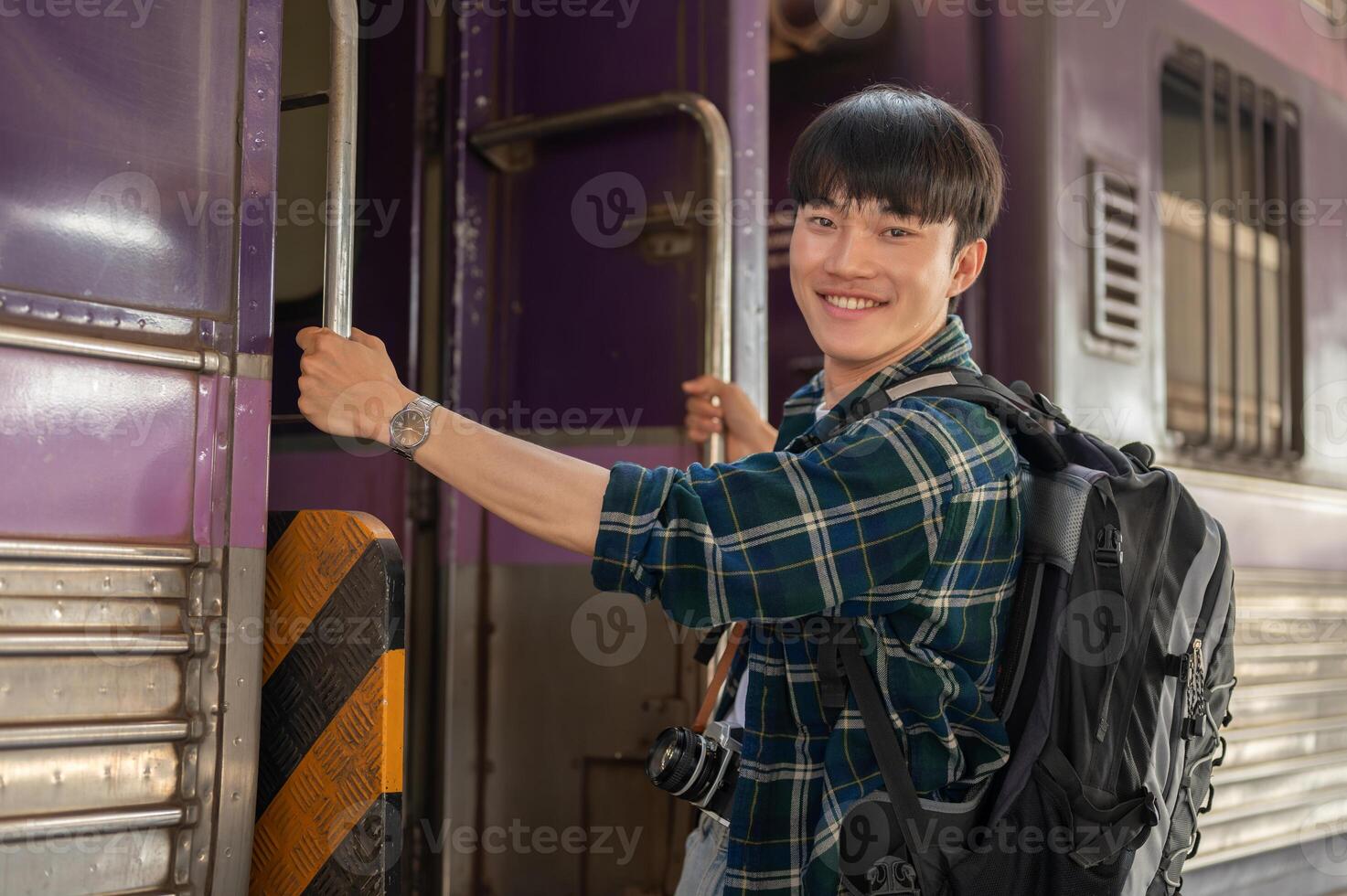 A happy Asian man backpacker is getting on the train, travel somewhere on his summer vacation. photo