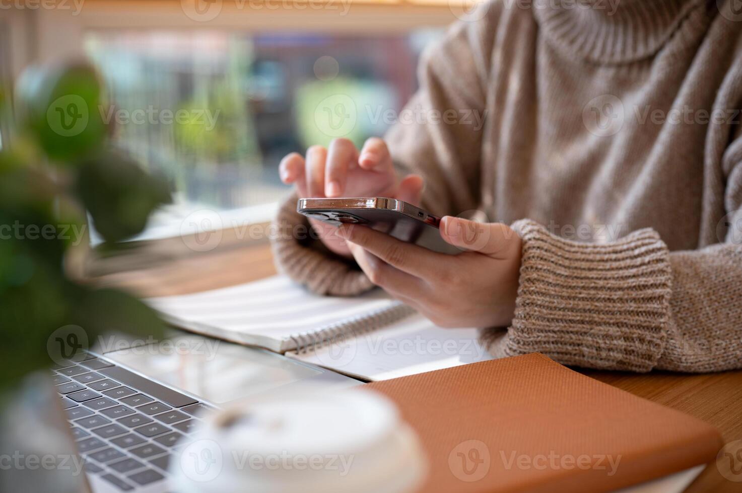 Cropped shot of a woman using her smartphone at a table at a cafe co-working space. photo