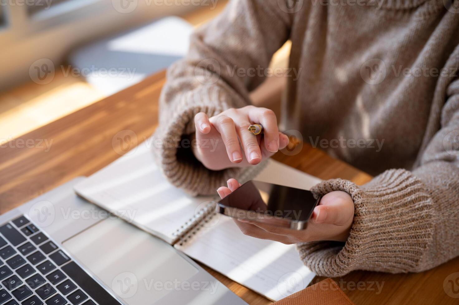 Cropped shot of a woman using her smartphone at a table at a cafe co-working space. photo