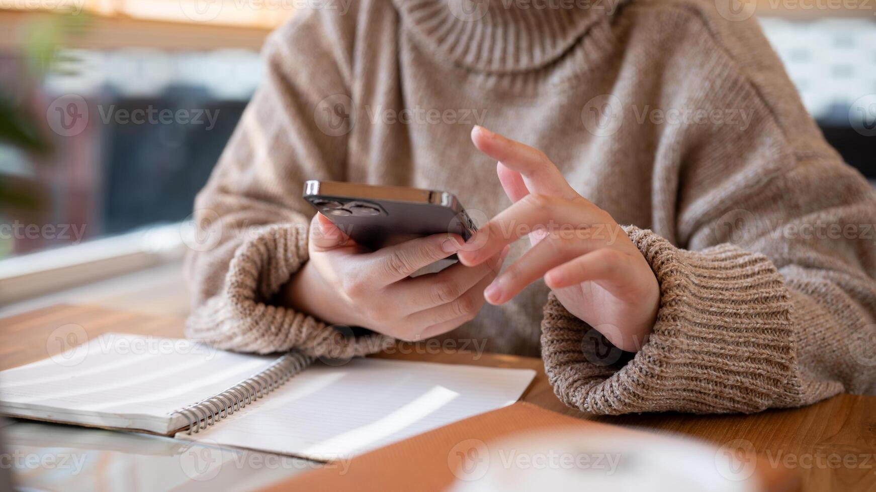 Cropped shot of a woman using her smartphone at a table at a cafe co-working space. photo