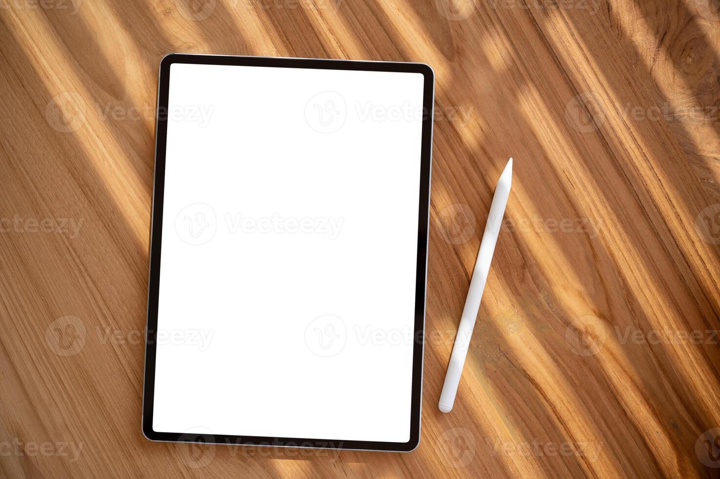 A wooden desk workspace with a white-screen digital tablet mockup and a tablet pen. photo