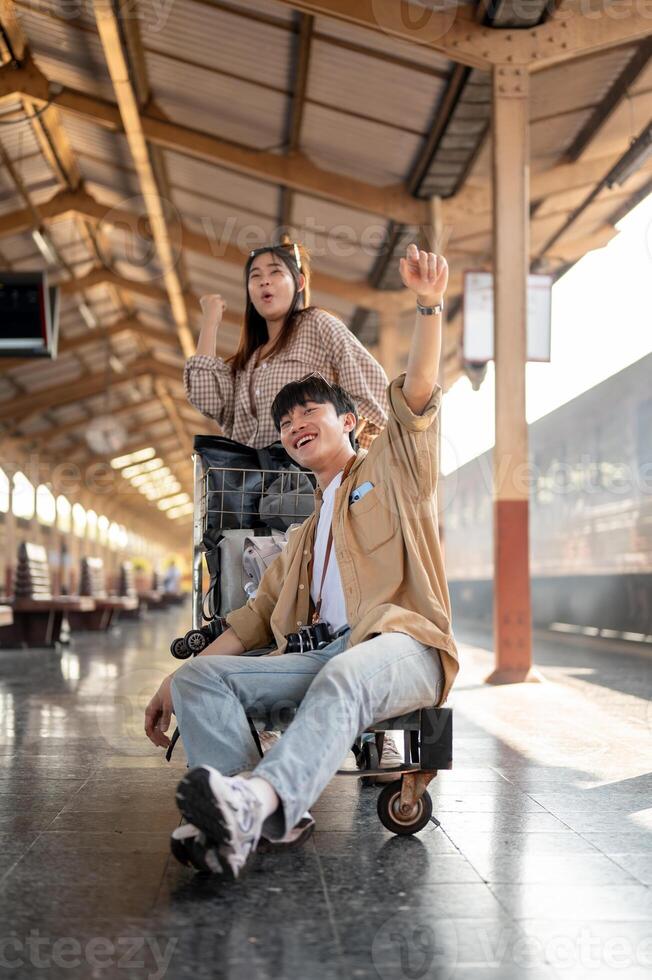 Lovely Asian couple are excited for their summer vacation, commuting by a train at a railway station photo