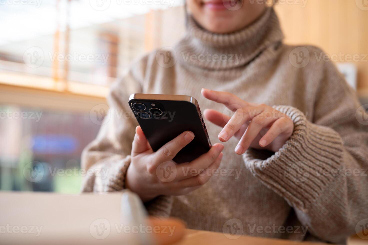 Cropped shot of a woman is checking messages on her phone while working remotely at a cafe. photo