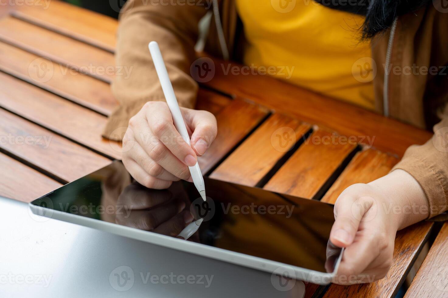 A close-up image of a woman holding a stylus pen, drawing or writing on her digital tablet. photo