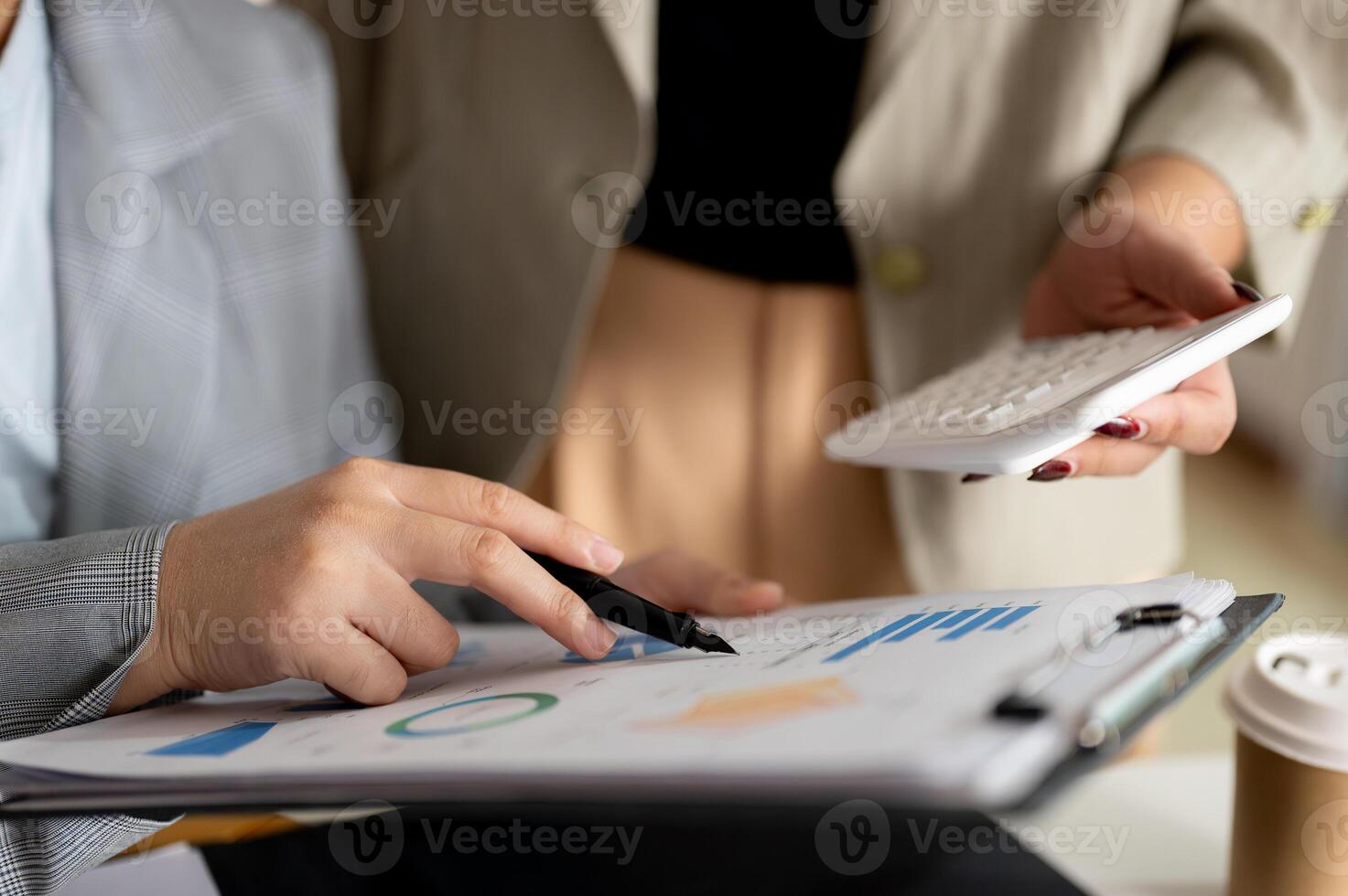 Two focused businesswomen or female accountants are brainstorming and working in the office together photo