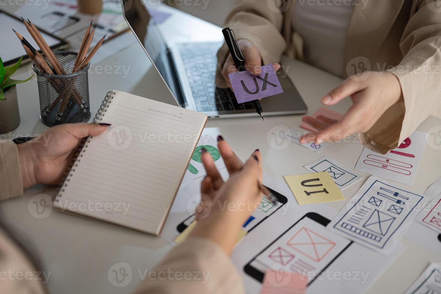 A meeting table with a team of creative UI UX graphic designers working on a mobile app prototype. photo