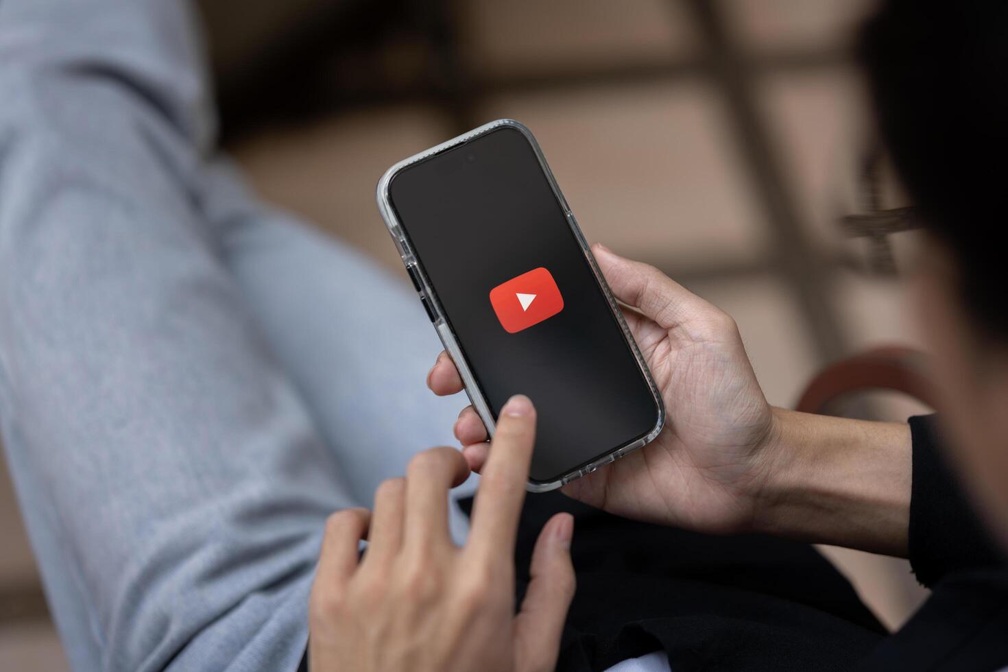 A man using Youtube application on his iPhone while sitting outdoors. close-up image photo