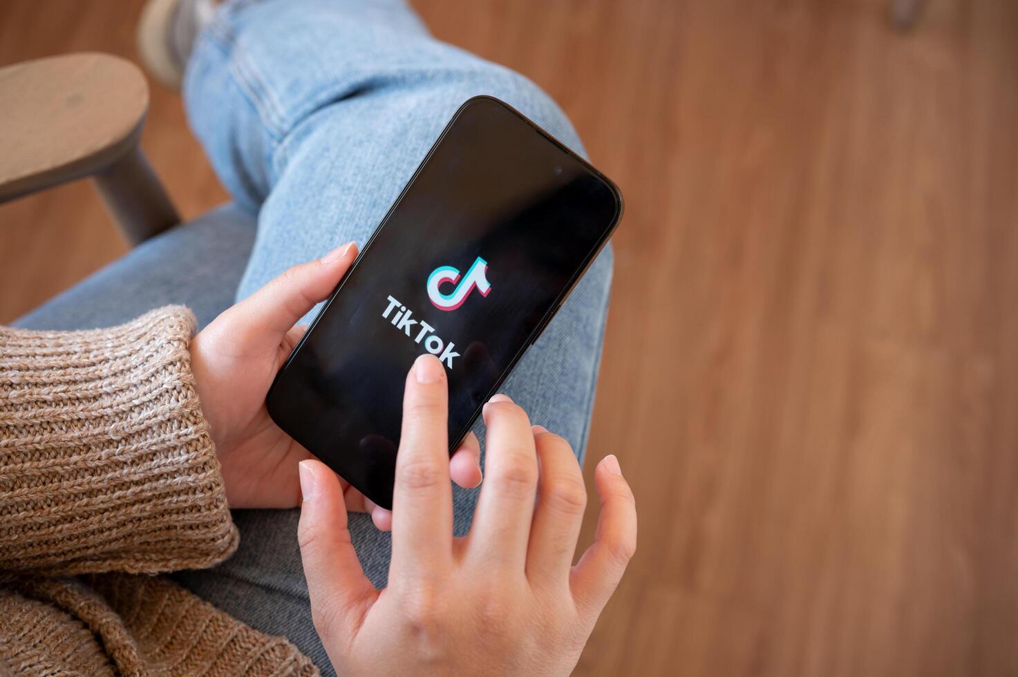 A woman is using TikTok app on her smartphone while relaxing indoors. photo