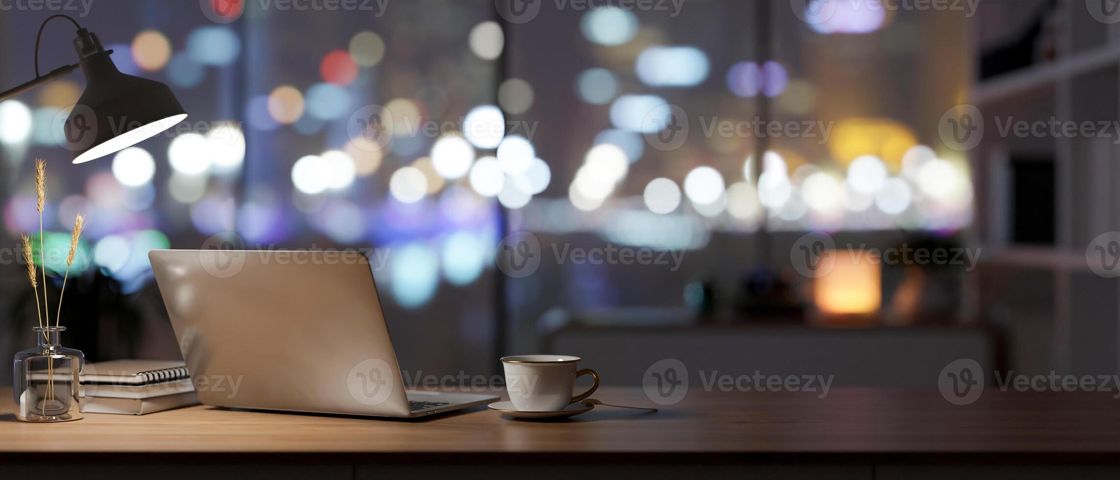 Back view of an office desk with a laptop, a table lamp, and accessories in a dark room at night photo