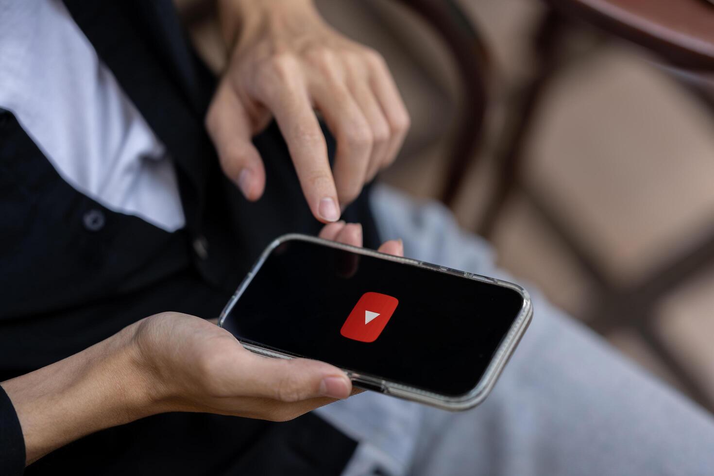 A man using Youtube application on his iPhone while sitting outdoors. close-up image photo