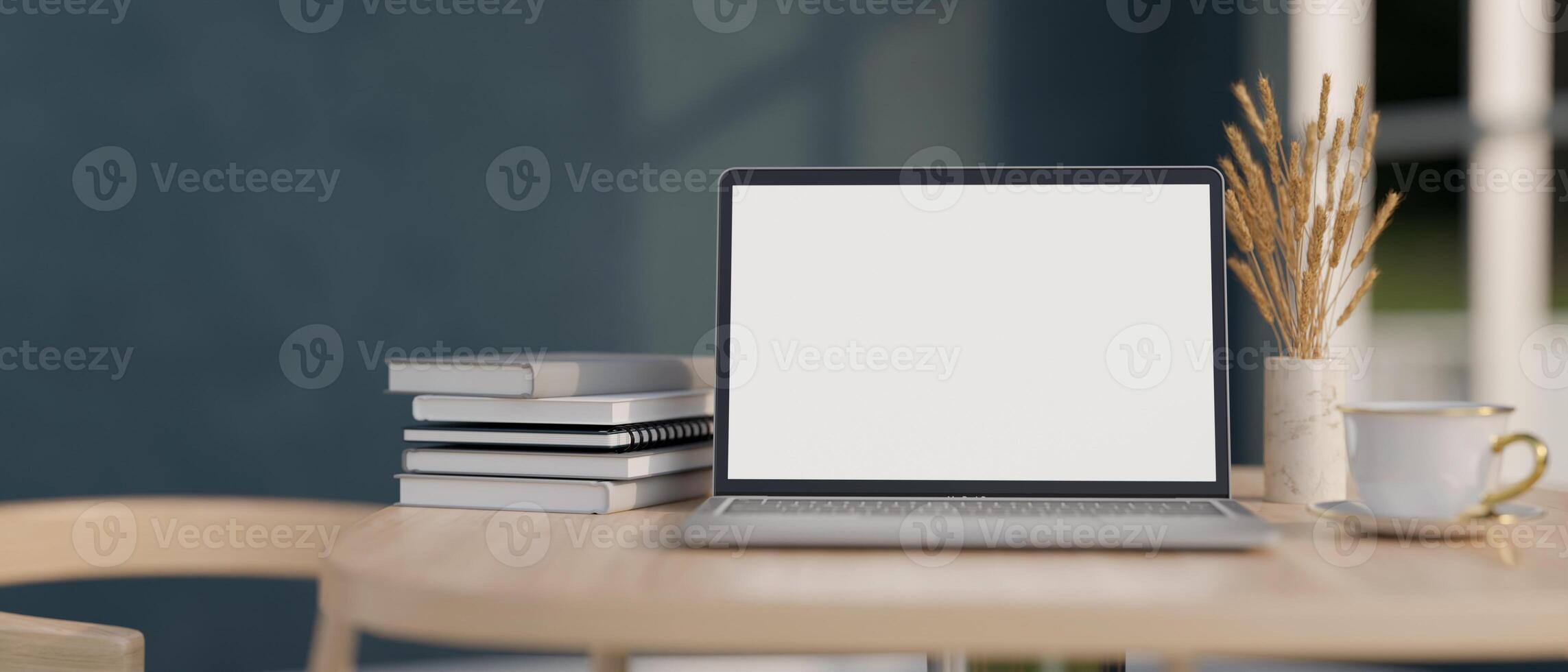Close-up image of a white-screen laptop computer, books, and a coffee cup on a wooden table indoors. photo