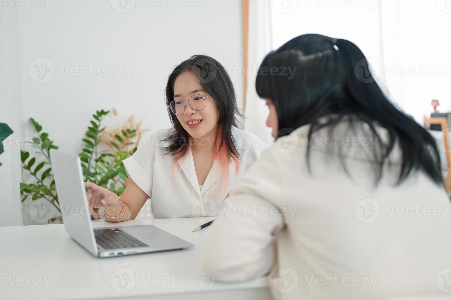 A young Asian female college student is co-working on a project with her classmate, discussing ideas photo