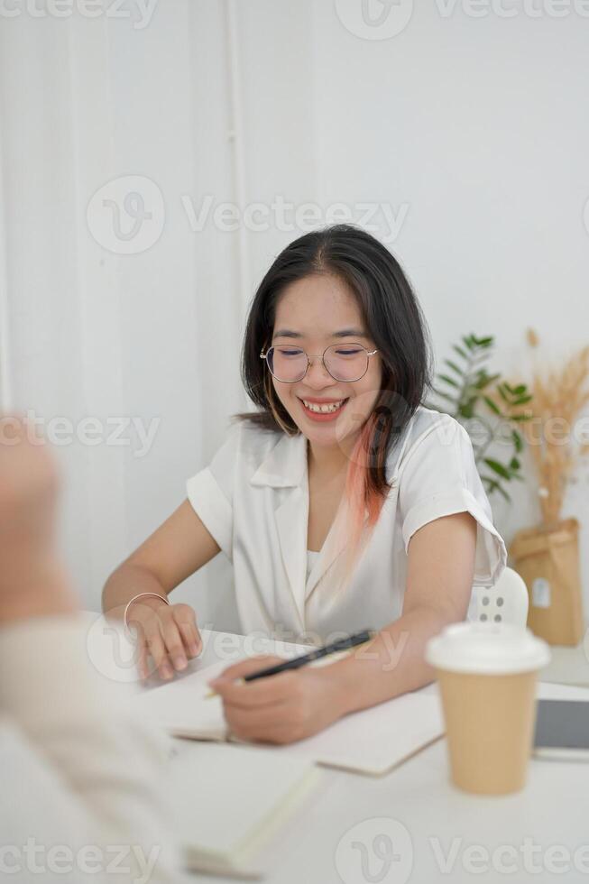 A young, friendly Asian female college student is helping her friend with math homework at a cafe. photo