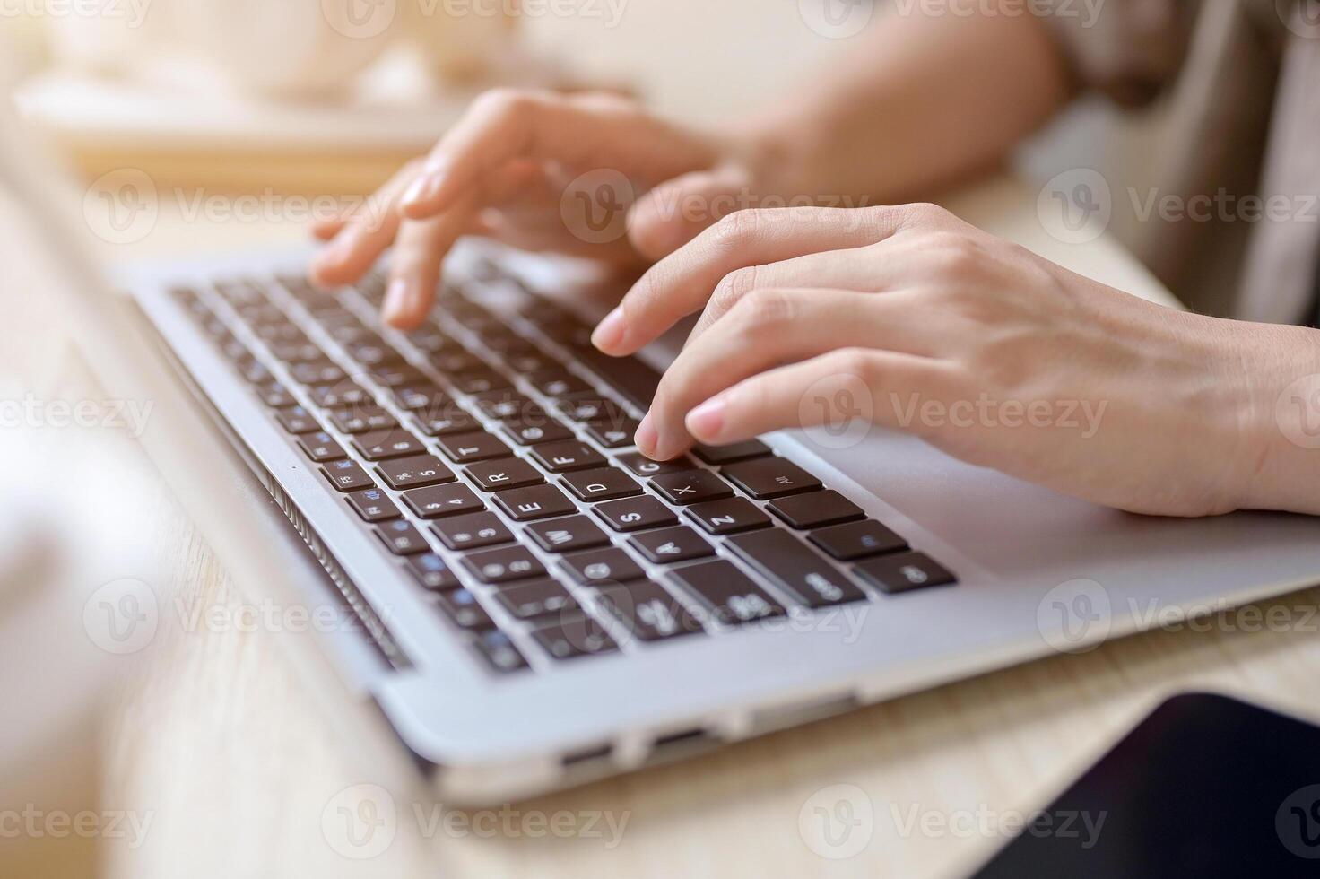 A close-up hand image of a woman working on her laptop computer, typing on the laptop keyboard. photo