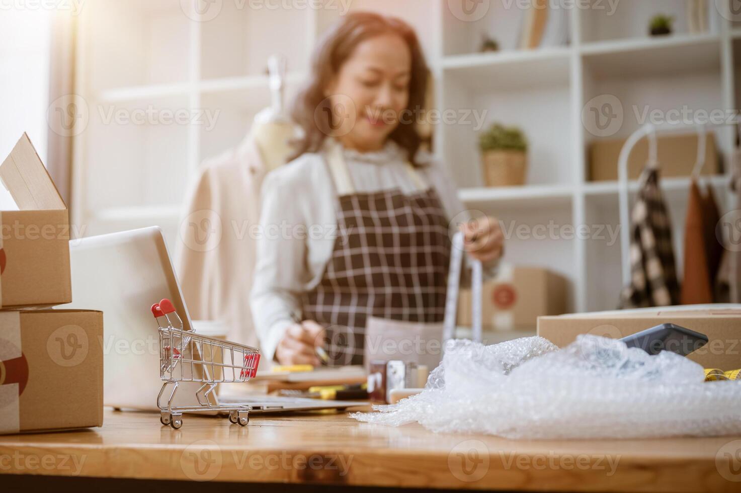 A shopping cart model, cardboard boxes, bubble wrap, computer, and equipment on a table. photo