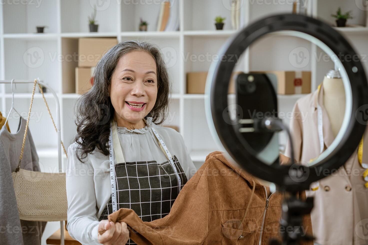 A female online seller is showing her goods live on her social media, selling clothes online. photo