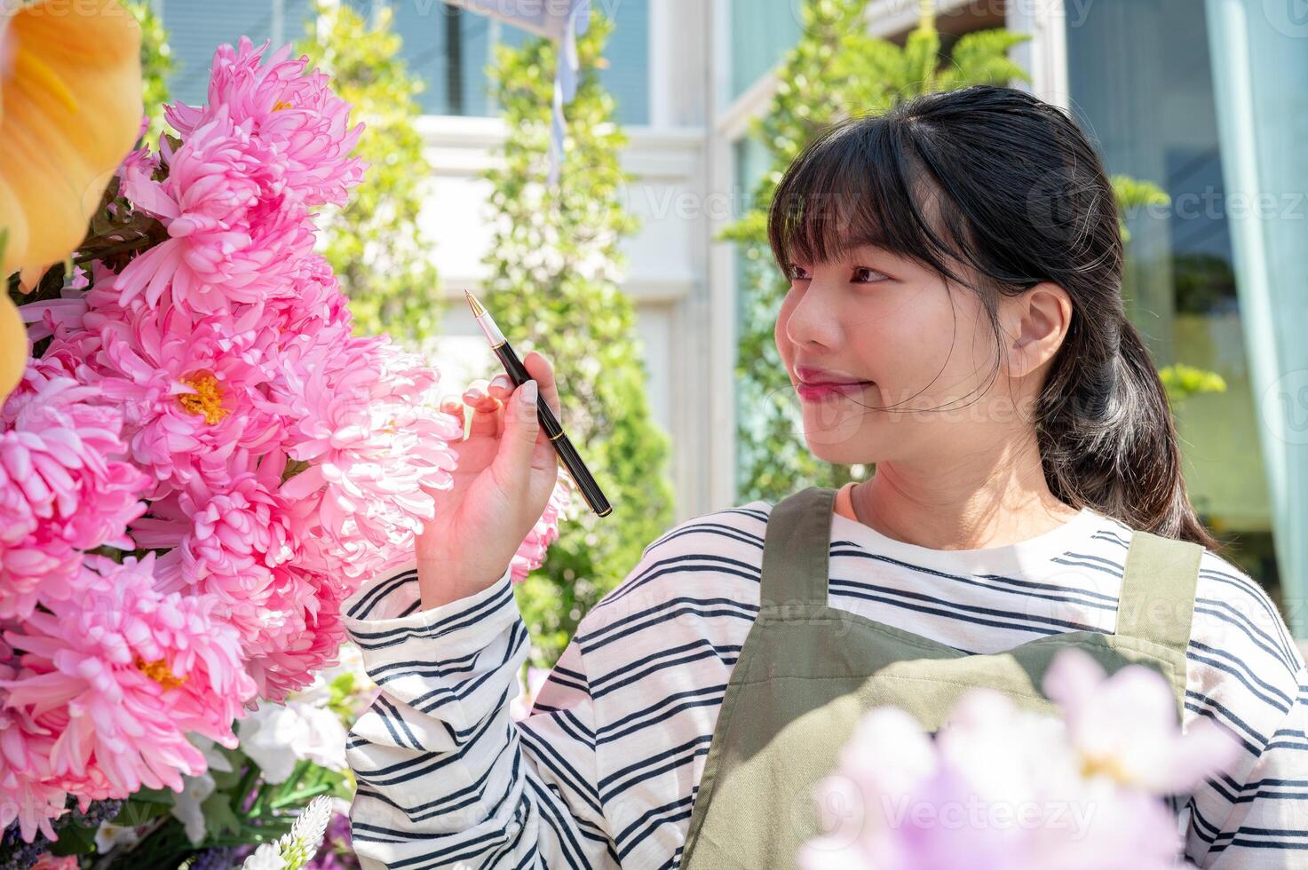 A positive Asian female florist or worker is checking orders and flower stocks in her shop. photo