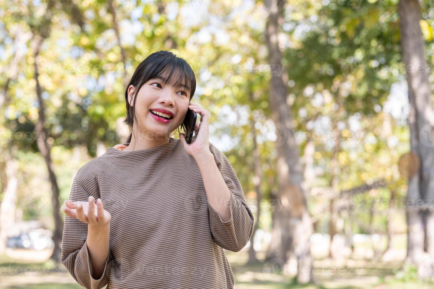 A woman enjoys talking on the phone with her friend while strolling around in the park. photo