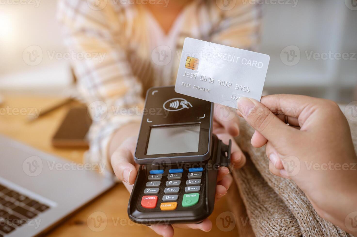 A close-up image of a customer tapping her credit card with a payment terminal in a clothing store. photo