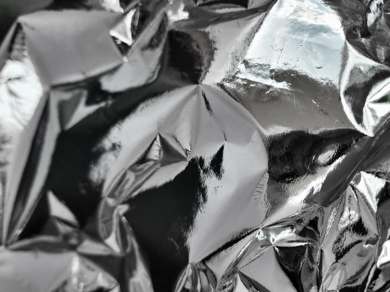 Thin sheet of silver leaf background with shiny crumpled uneven surface photo