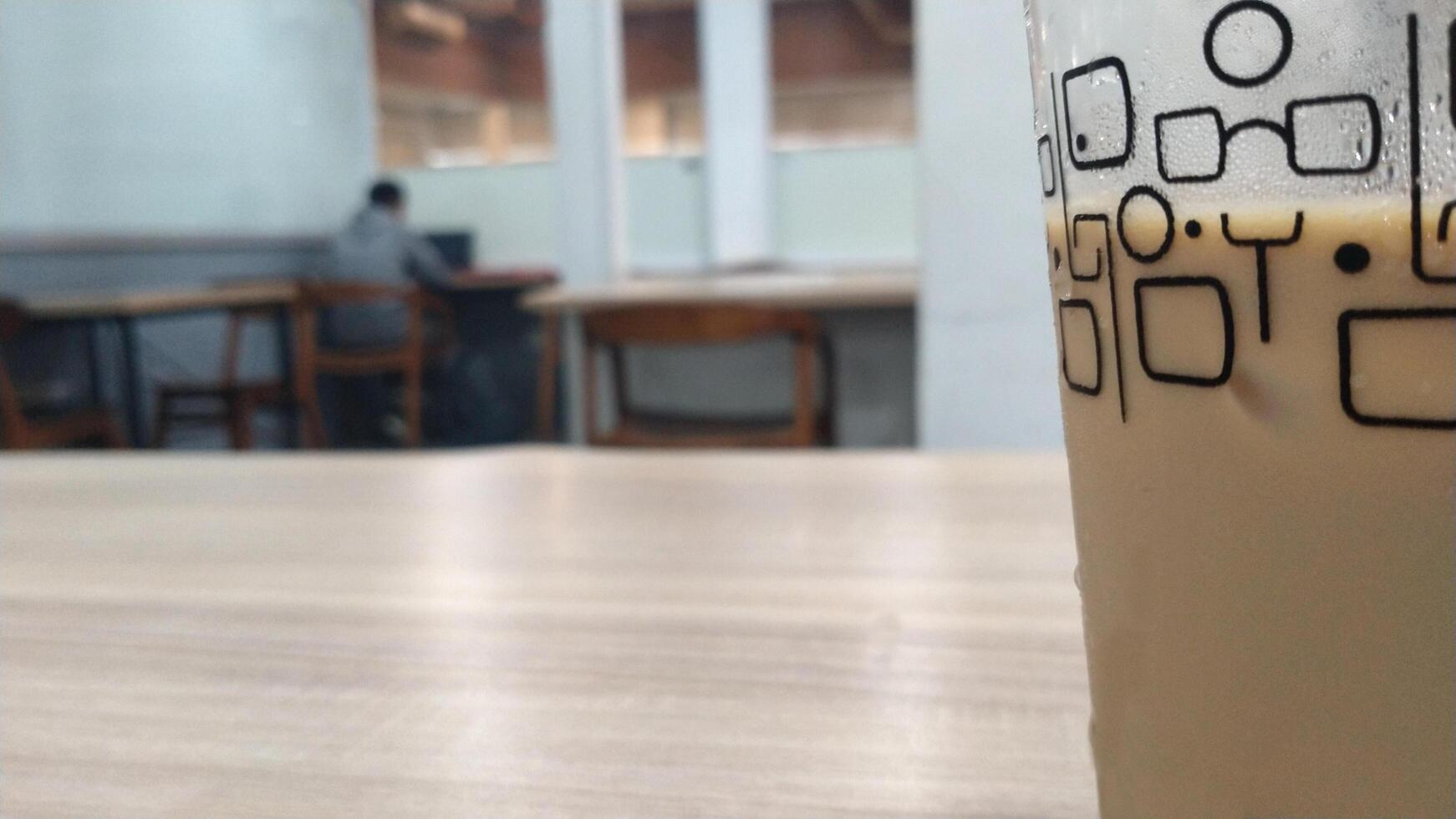 Close up cold espresso coffee on the table, selective focus with one man behind. Blurred background. Copy space for text ad photo