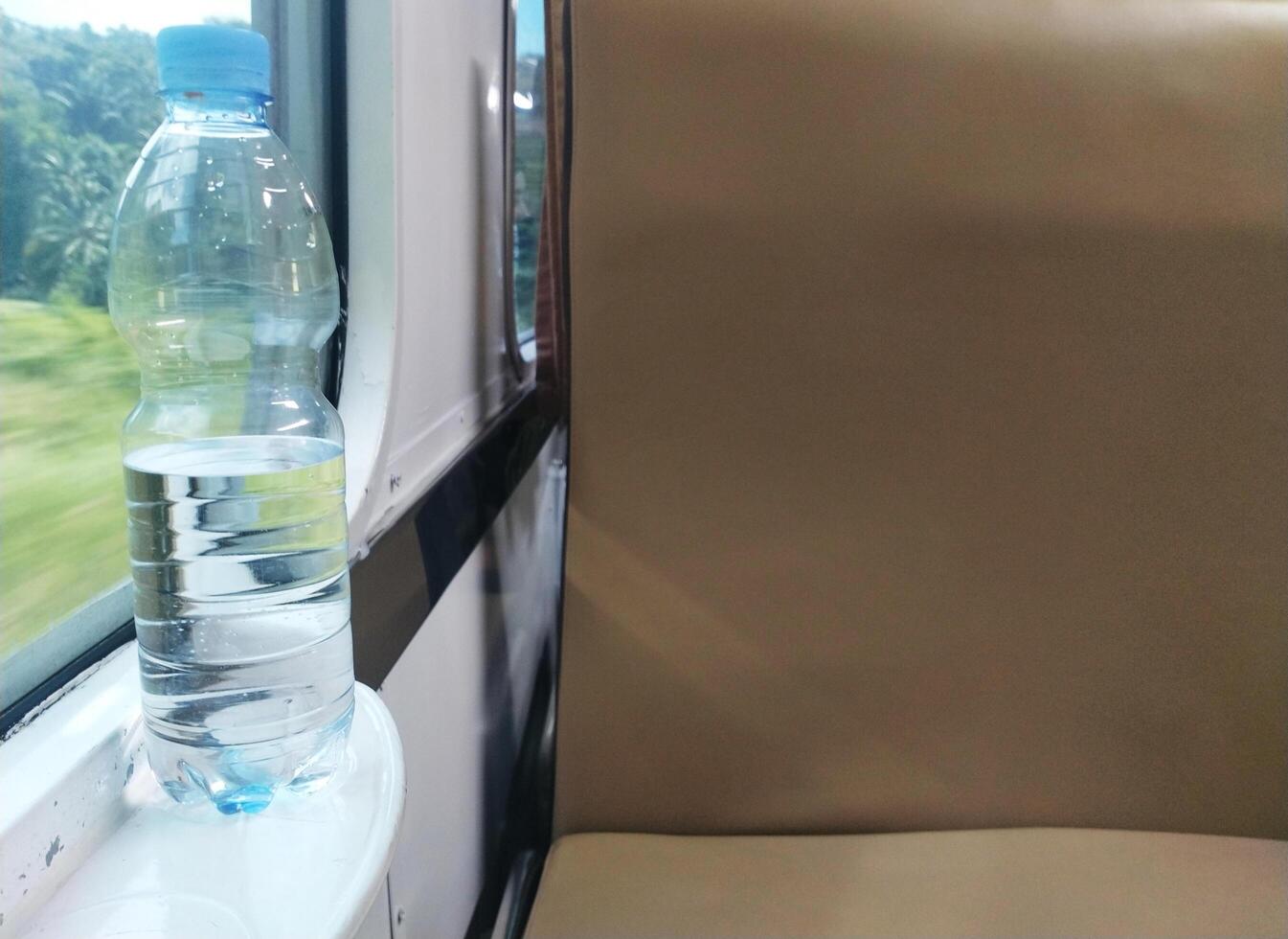 Close up view of mineral water bottle standing near train window. Stay fresh during the trip. photo