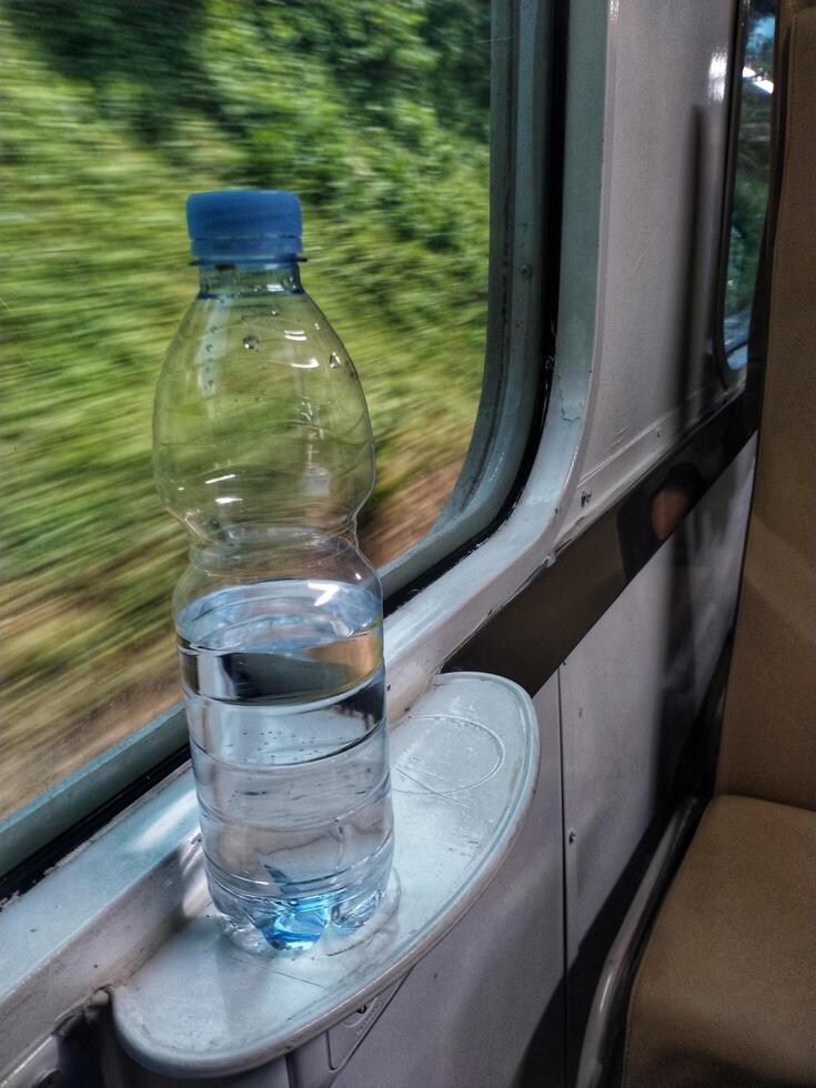 Close up view of mineral water bottle standing near train window. Stay fresh during the trip. photo