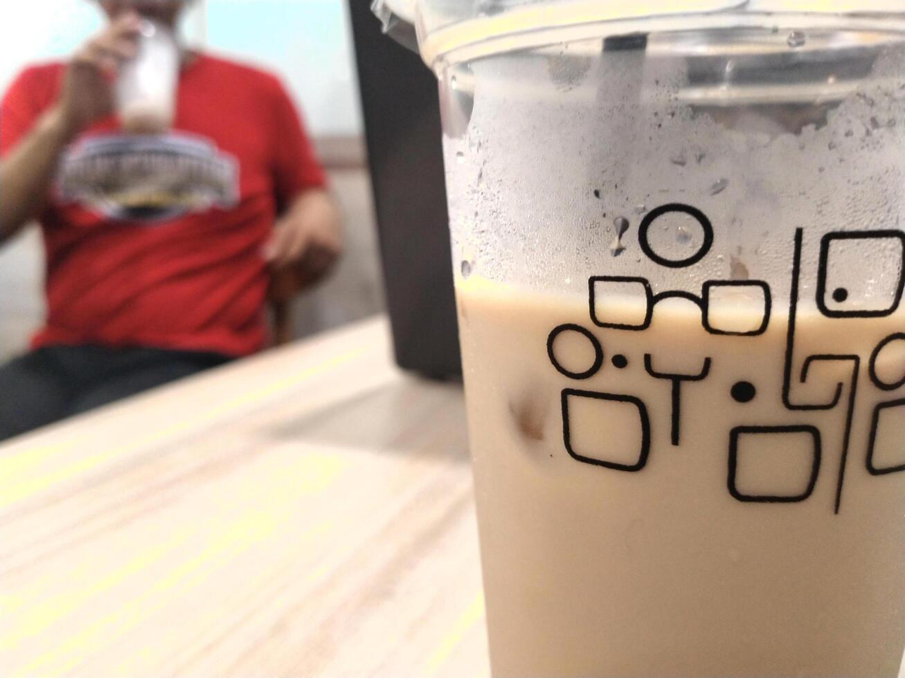 Close up cold espresso coffee on the table, selective focus with one man behind. Blurred background. Copy space for text ad photo