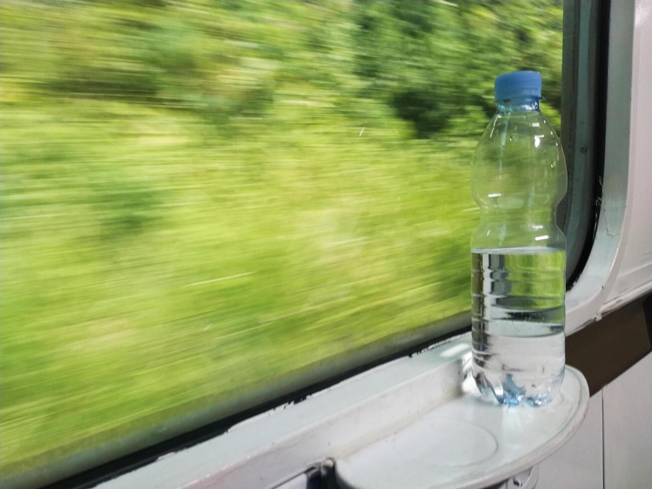 Close up view of mineral water bottle standing near train window. Stay fresh during the trip. photo