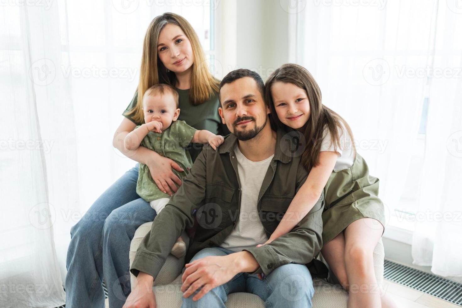 Happy family at home. Mother father two children daughters relaxing indoor. Mom dad parents baby girls kids relax playing having fun together. Family smiling laughing enjoying tender love moment photo