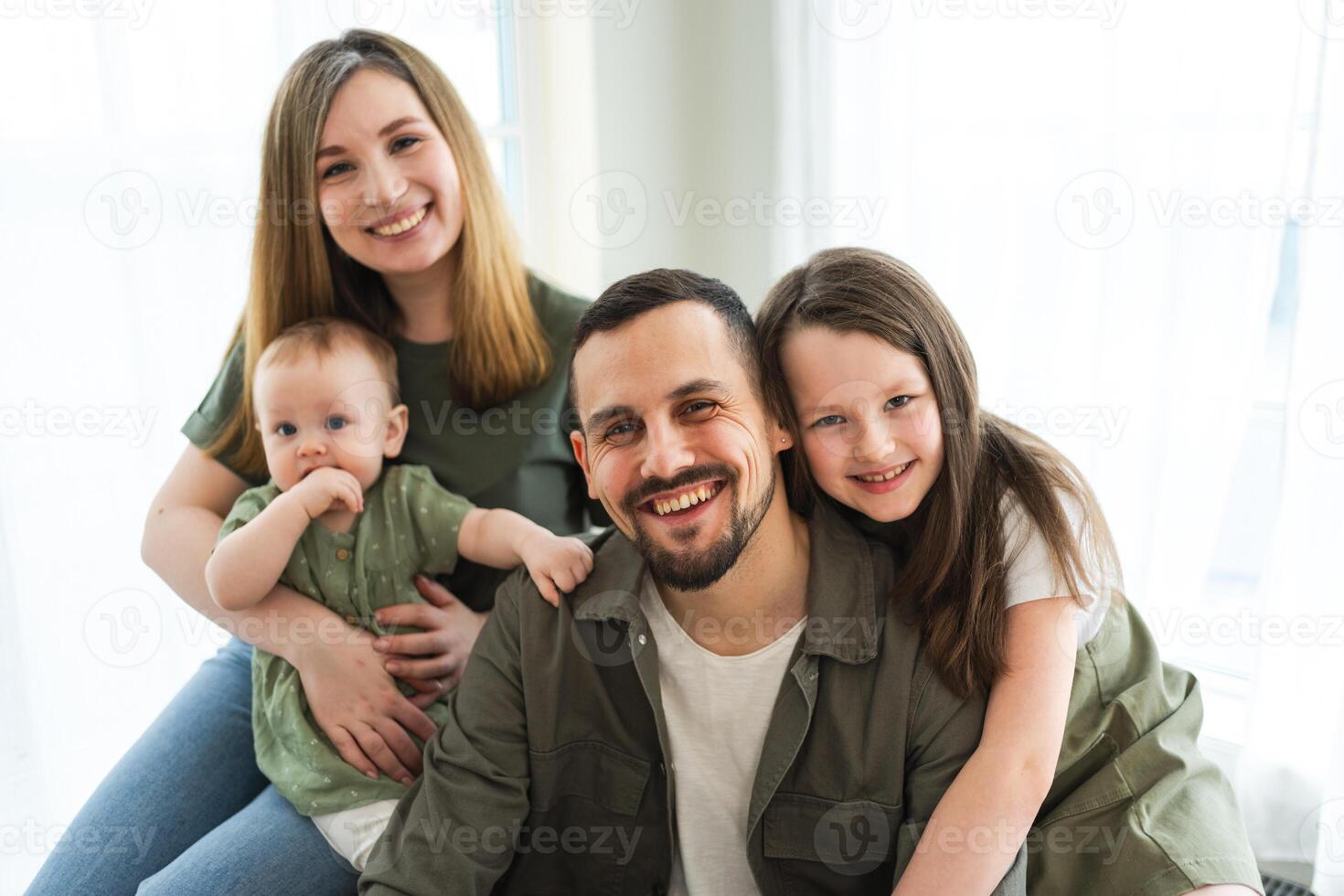 Happy family at home. Mother father two children daughters relaxing indoor. Mom dad parents baby girls kids relax playing having fun together. Family smiling laughing enjoying tender love moment photo