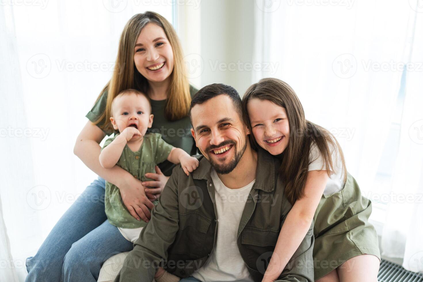 Happy family at home. Mother father two children daughters relaxing indoor. Mom dad parents baby girls kids relax playing having fun together. Family smiling laughing enjoying tender love moment photo