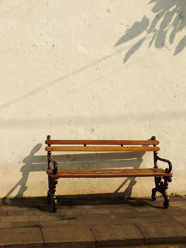 Old wooden bench in front of old dirty white wall. Retro vintage concept background image. Oldies but goodies photo