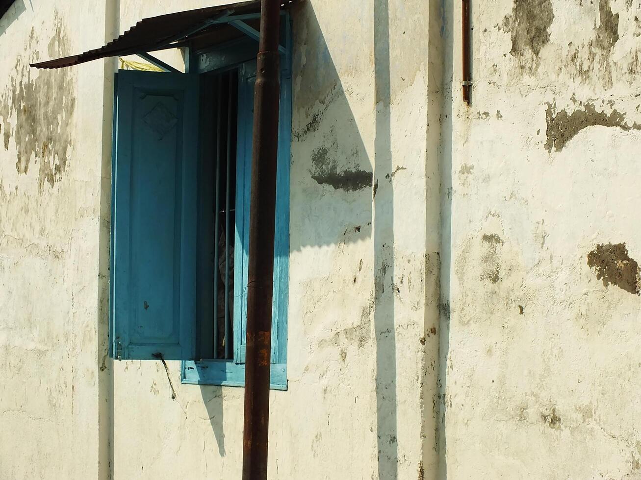 ancient and antique blue wooden window with cracking old wall around it photo