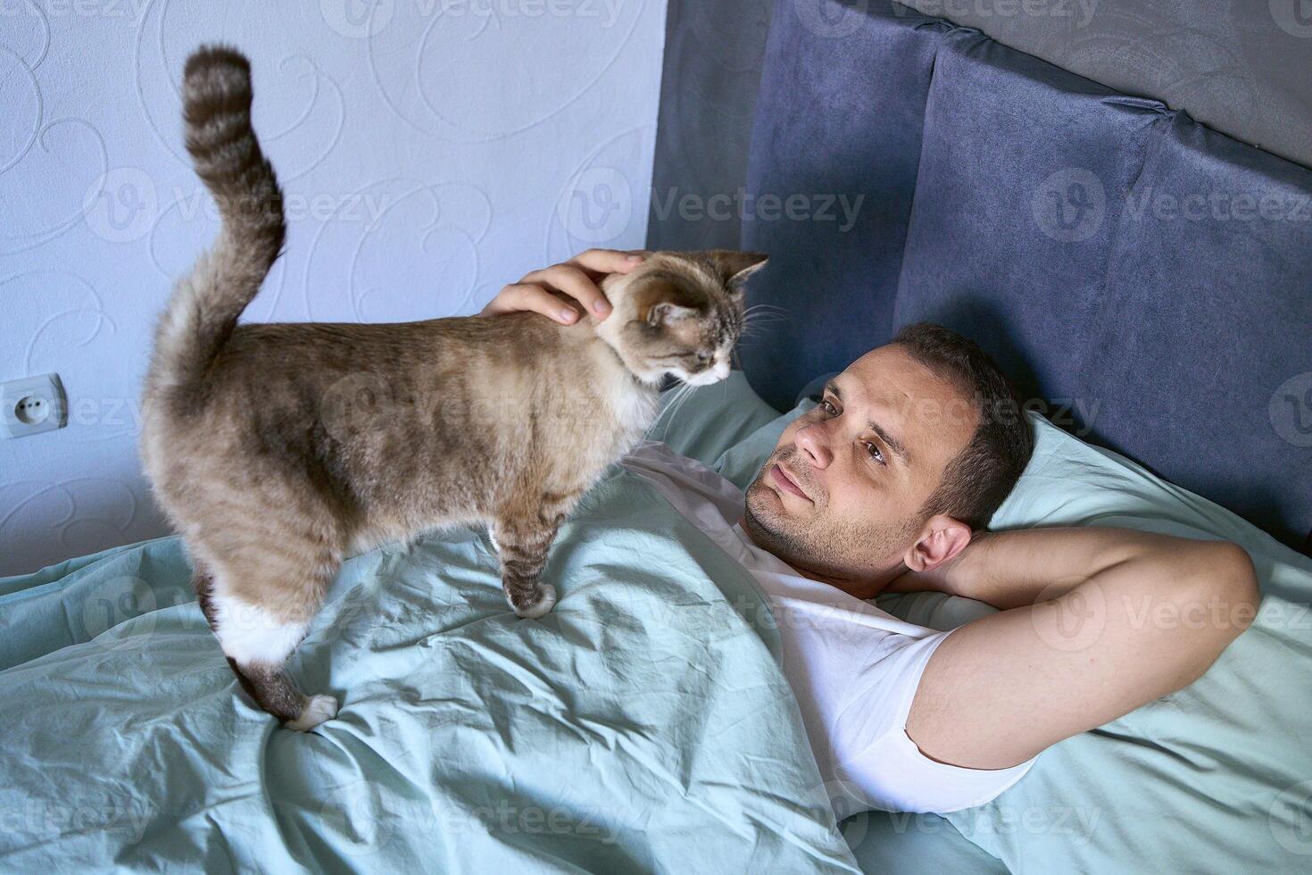 a young man sleeping with a cat on his chest, morning routine photo