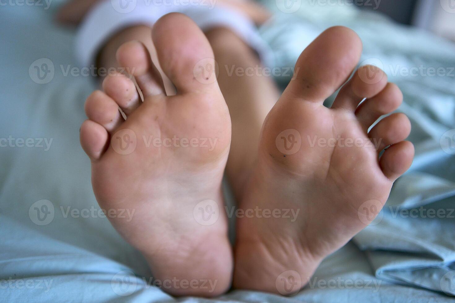 man is lying on a bed, big feet on the bed photo