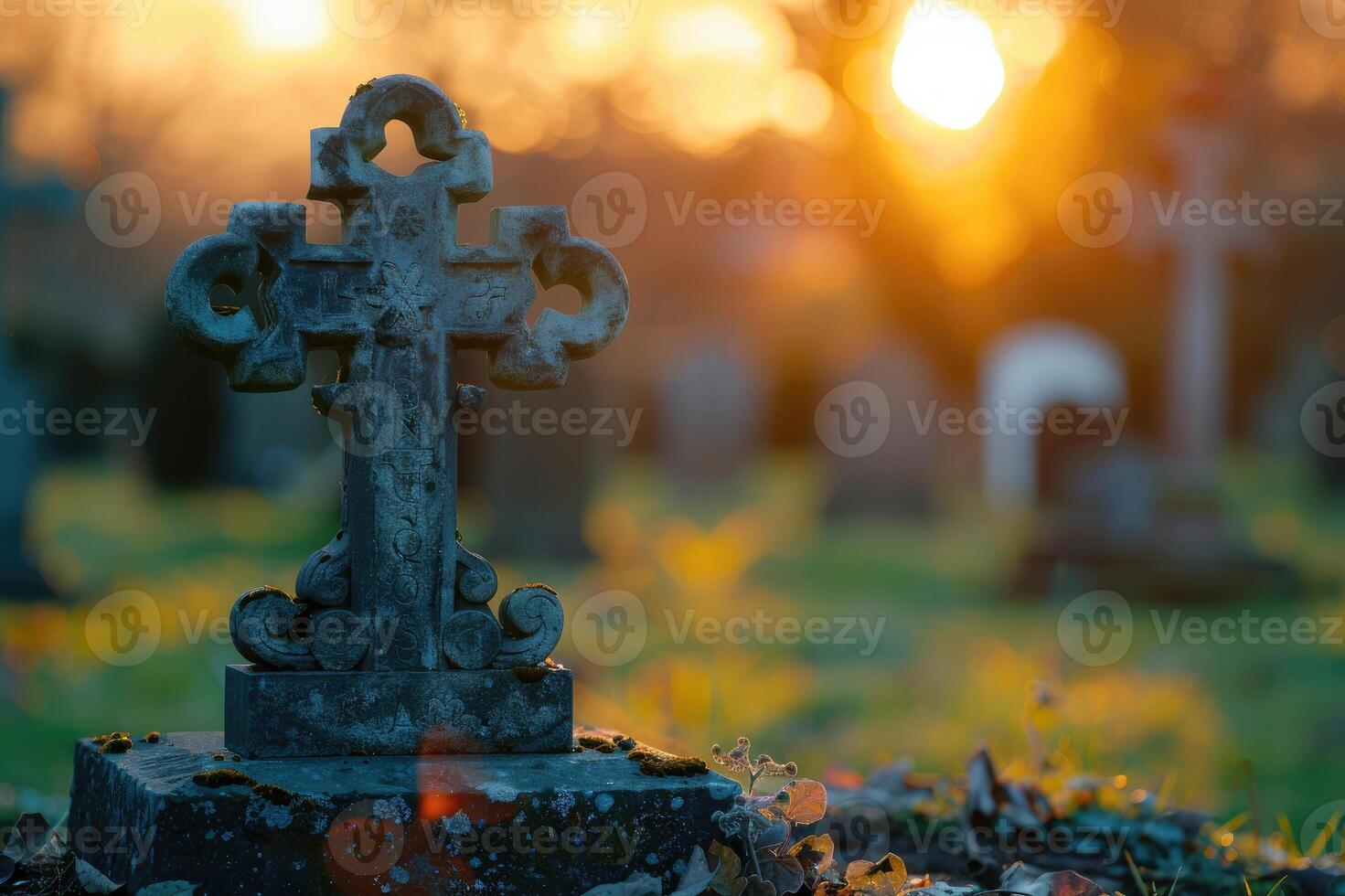 An old stone cross with intricate designs, surrounded by orange flowers and foliage in a serene graveyard scene photo